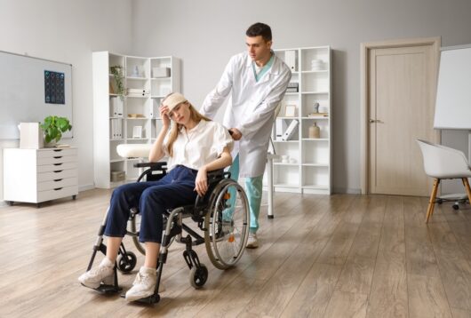 Young woman with brain concussion in wheelchair and doctor at hospital